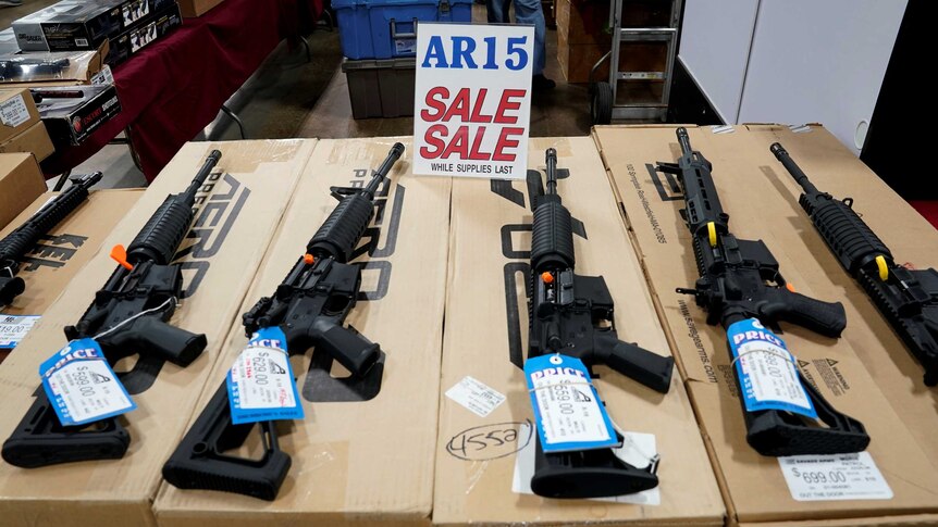 AR-15 rifles sit on boxes displayed for sale.