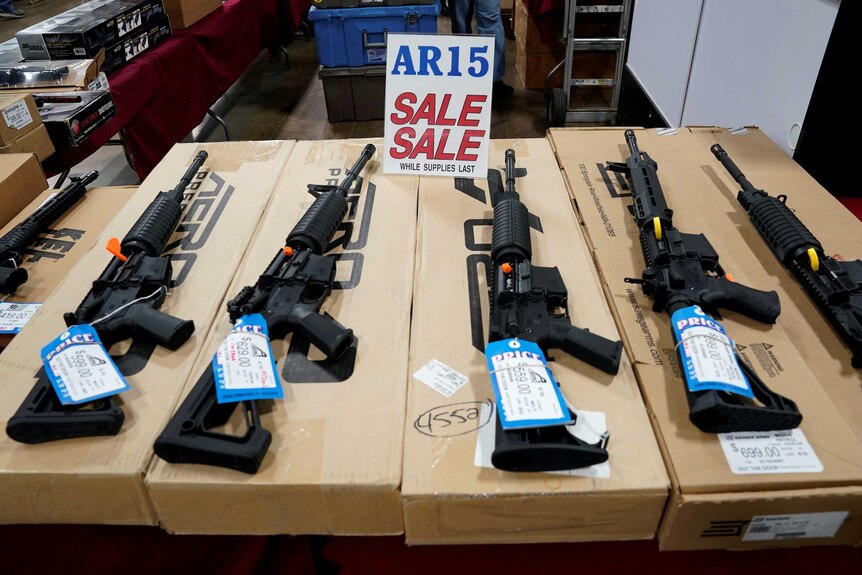 AR-15 rifles sit on boxes displayed for sale.