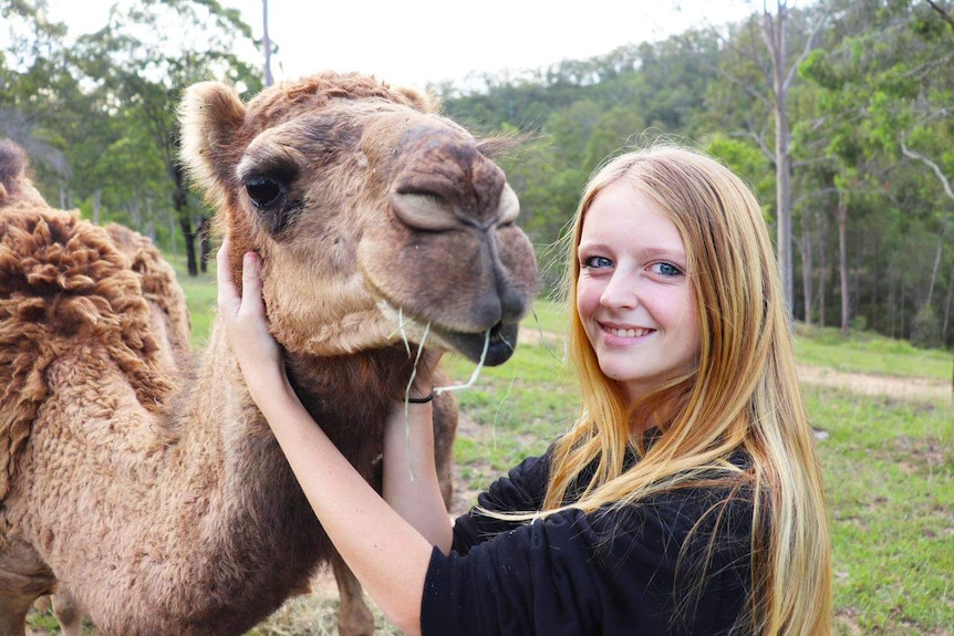 A photo of teenager Courtney Mitchell patting a pet camel.