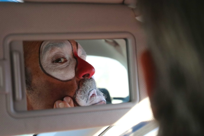 "Hollywood" Harris puts on his sad clown makeup in his car's mirror.