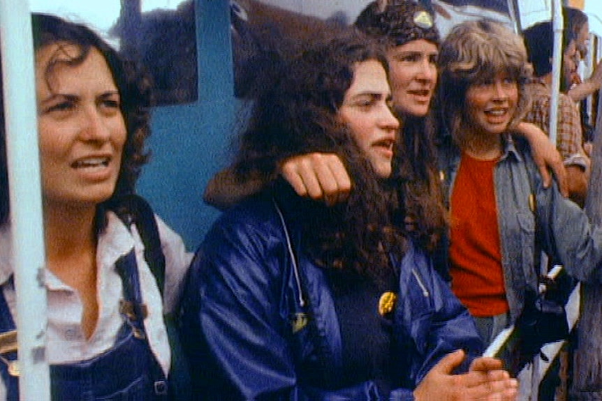 A group of young women singing on the side of a boat.