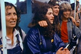 A group of young women singing on the side of a boat.