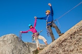Couple climbing up a rocky cliff together