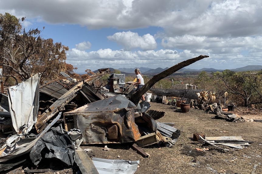 Mangled and burnt metal contrasts a blue sky and a view of the Byfield Ranges.