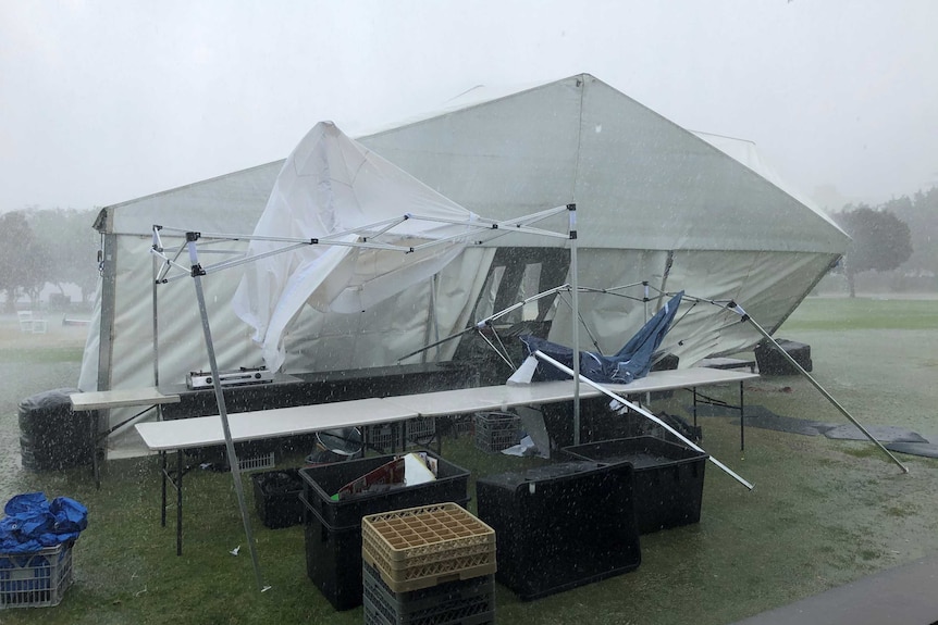 A marque is toppled over exposing tables and other belongings to the elements.