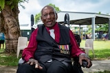 Elderly Indigenous man in wheelchair smiling and wearing his military medals 