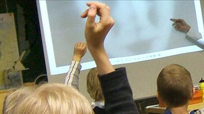 Primary school students raise their hands in the classroom
