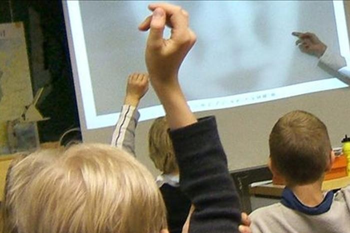 Primary school students raise their hands in the classroom