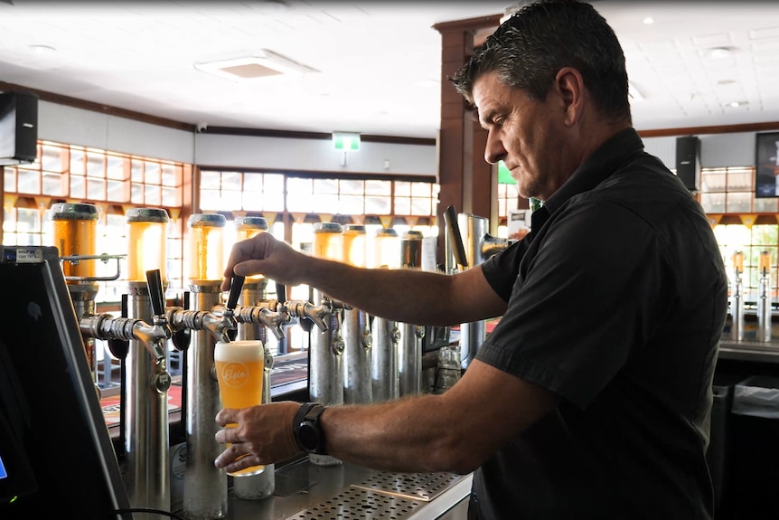 A man pours beer from tap in a pub