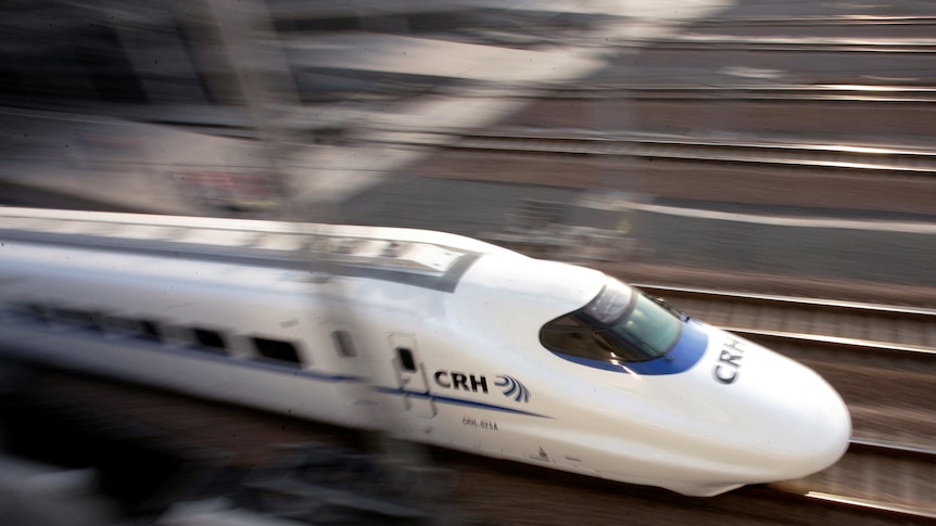 A white bullet train zooms through the tracks.