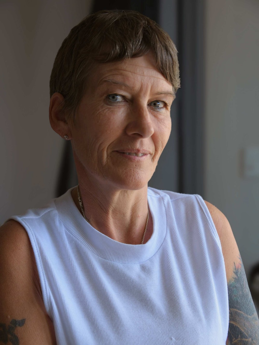 A woman with folded arms looks into the camera.