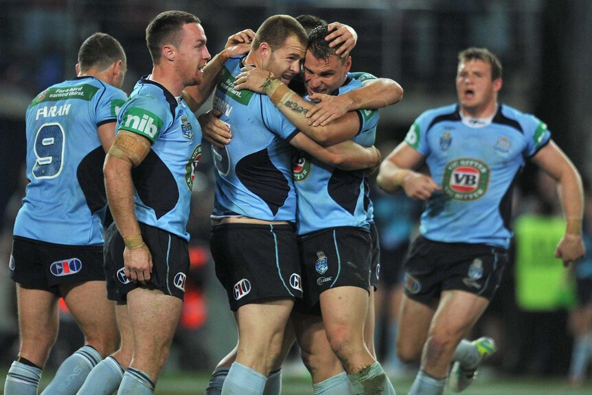 Blues players celebrate Trent Merrin's (centre) try