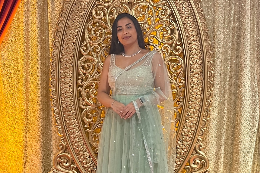 Woman standing in front of a golden curtain.