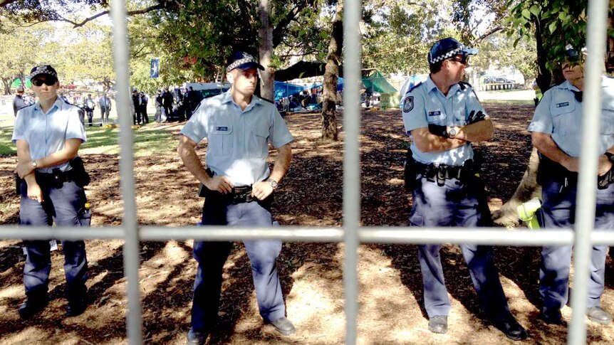 Police stand guard behind a fence in South Brisbane's Musgrave Park