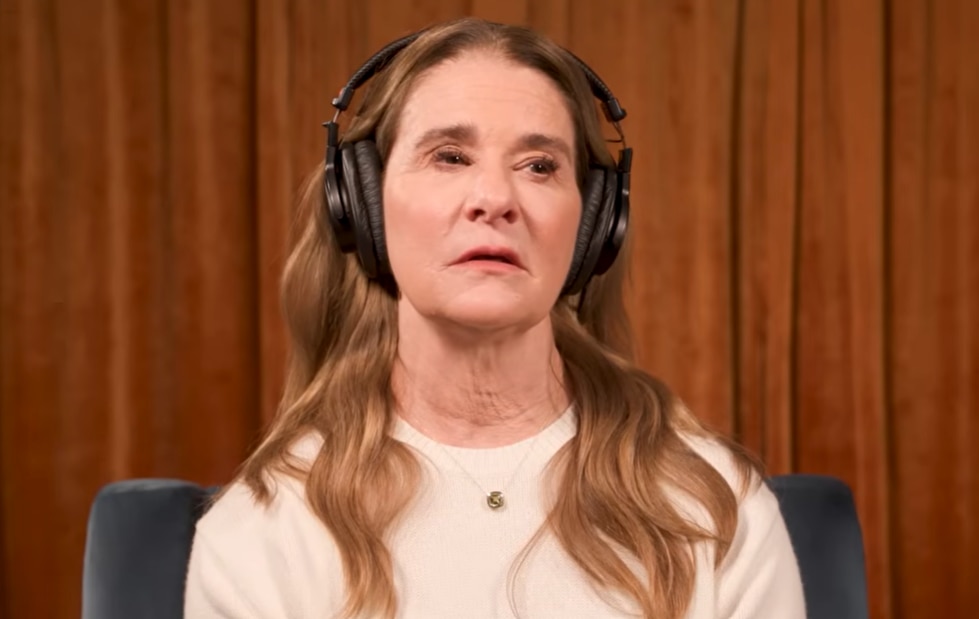 A screenshot of a video showing Melinda Gates wearing headphones. She's got long brown hair and brown eyes. 
