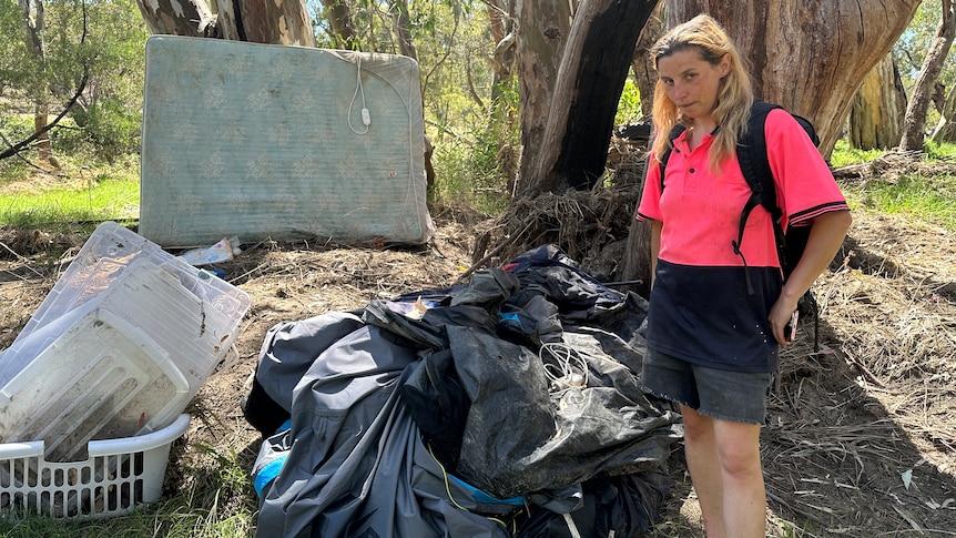 a photo of a woman standing next to possessions on camping site 