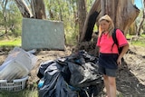 a photo of a woman standing next to possessions on camping site 