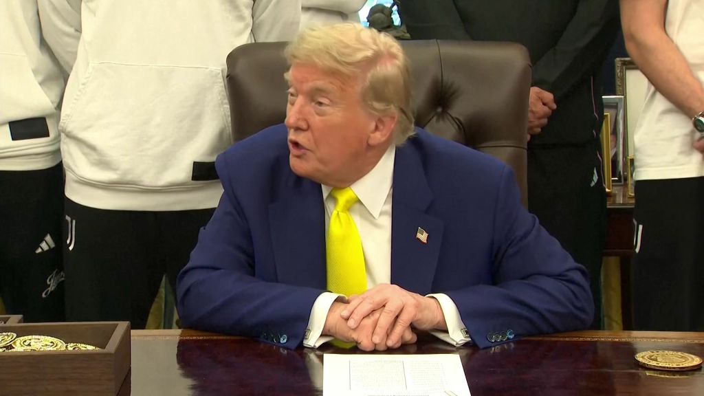Donald Trump speaking at his desk in a yellow tie. 