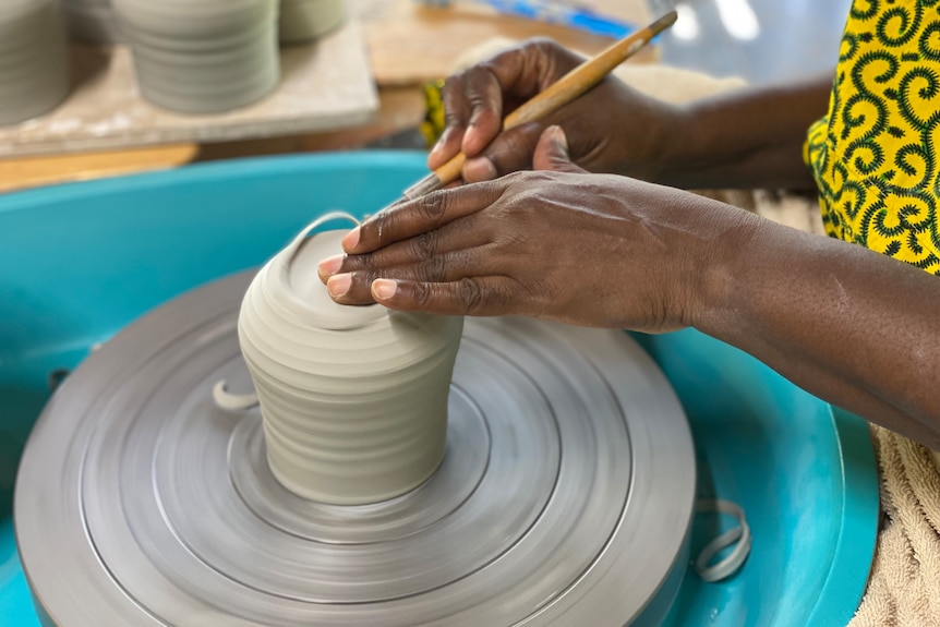 A woman works on a ceramic creation.