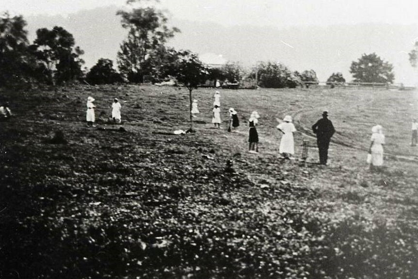 Black and white photo of girls playing vigoro in a field.