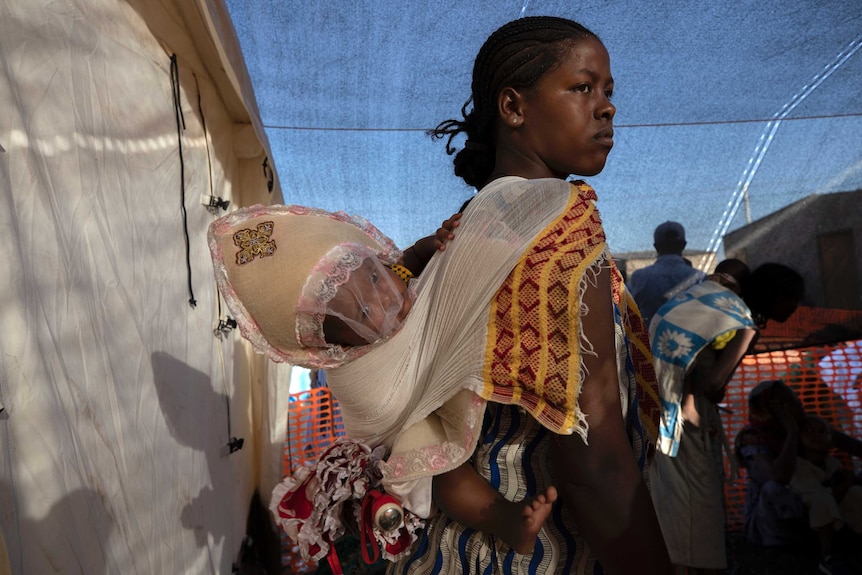 A woman with a baby on her back.