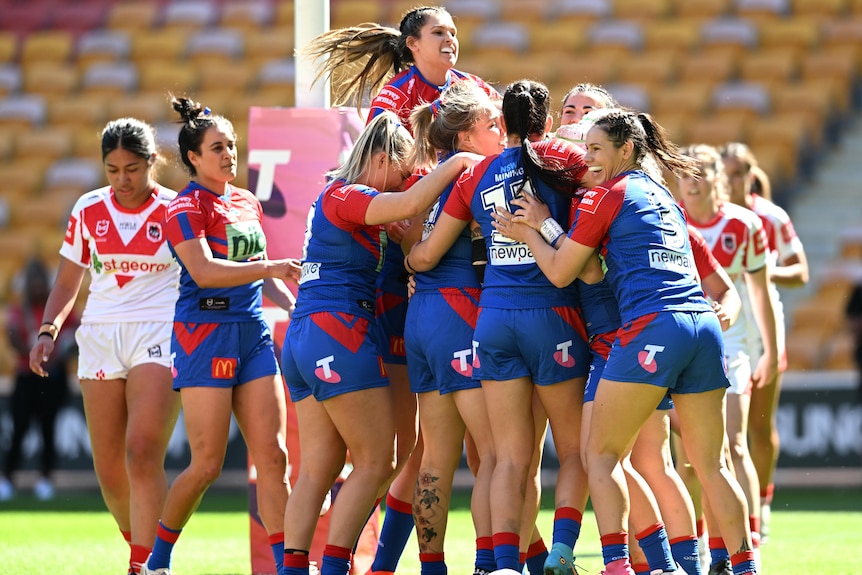A group of Newcastle Knights NRLW players embrace as they celebrate a try.