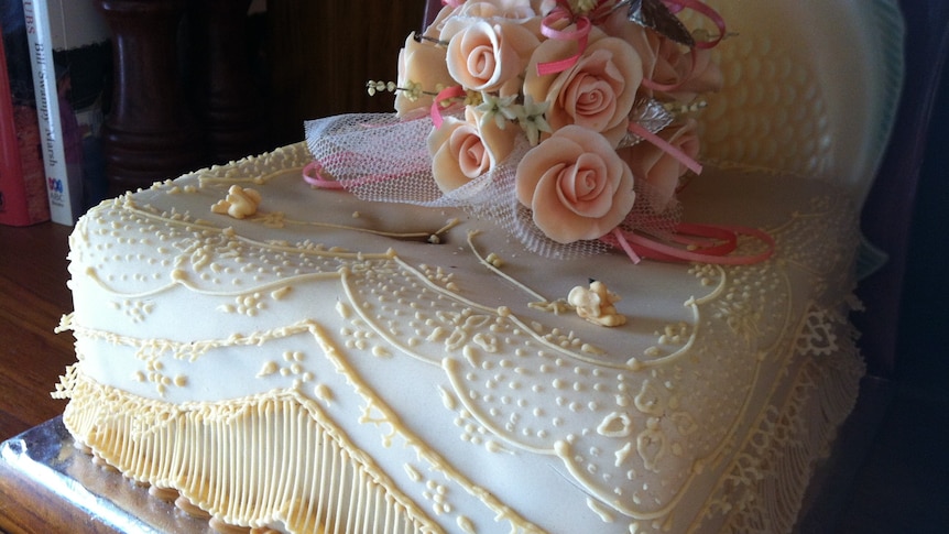 wedding cake with floral arrangement and ribbons on top