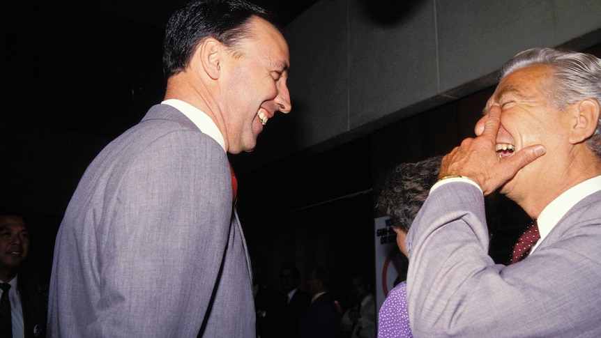 Paul Keating and Bob Hawke face each other laughing enthusiastically.