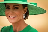 A close up image of Kate, Princess of Wales, wearing a large green hat.