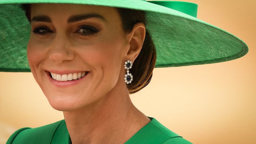 A close up image of Kate, Princess of Wales, wearing a large green hat.