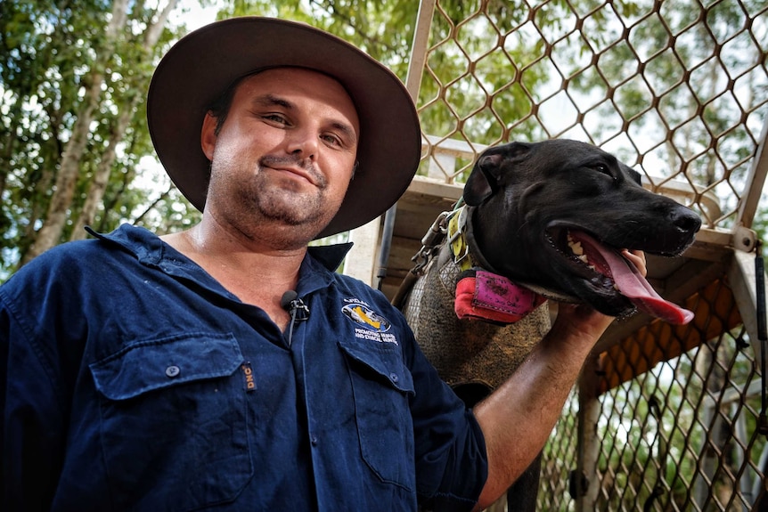 Man stands holding dog