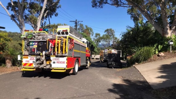 A fire truck parked on the side of a small road with another truck further down the road