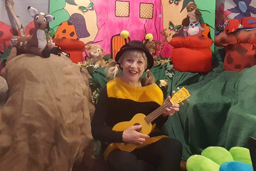 A woman dressed as a bee holding a ukulele