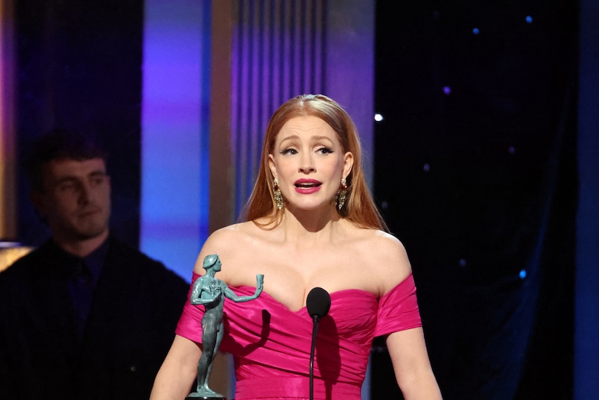 Jessica Chastain con un vestido rosa hablando en el escenario