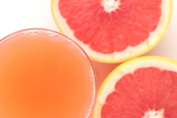 A glass of grapefruit juice and some cut fruit.