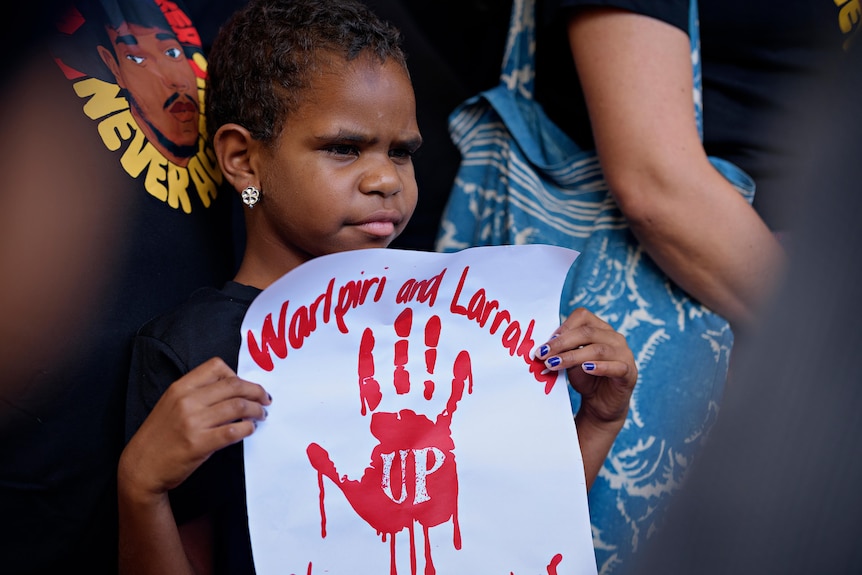 a young Aboriginal child holding a sign
