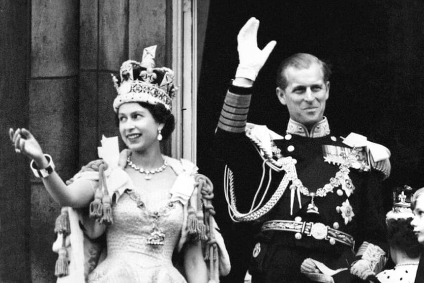 A black and white photograph of Queen Elizabeth II and Prince Philip waving from a balcony.