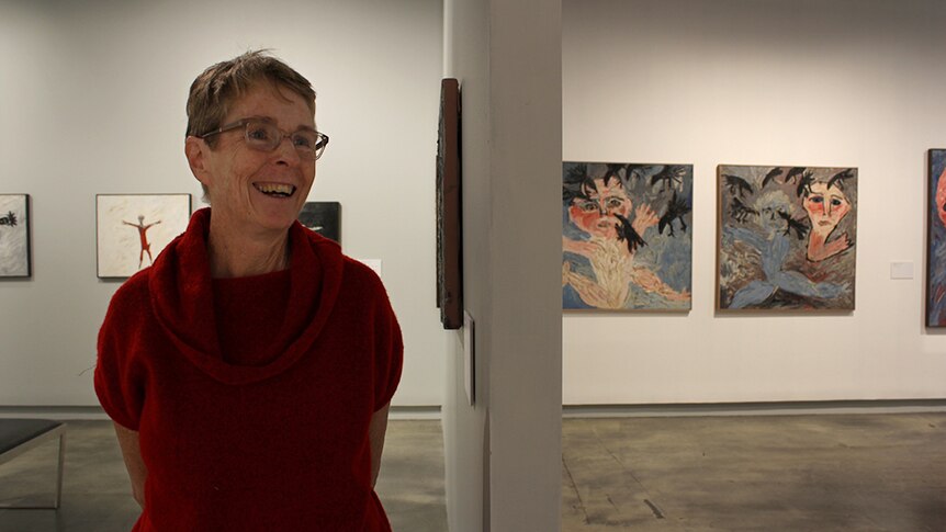 Painter Davida Allen standing inside a gallery space surrounded by paintings.
