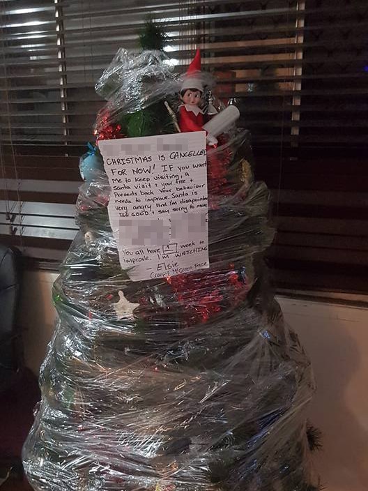 A Christmas tree wrapped in plastic with a note attached to it