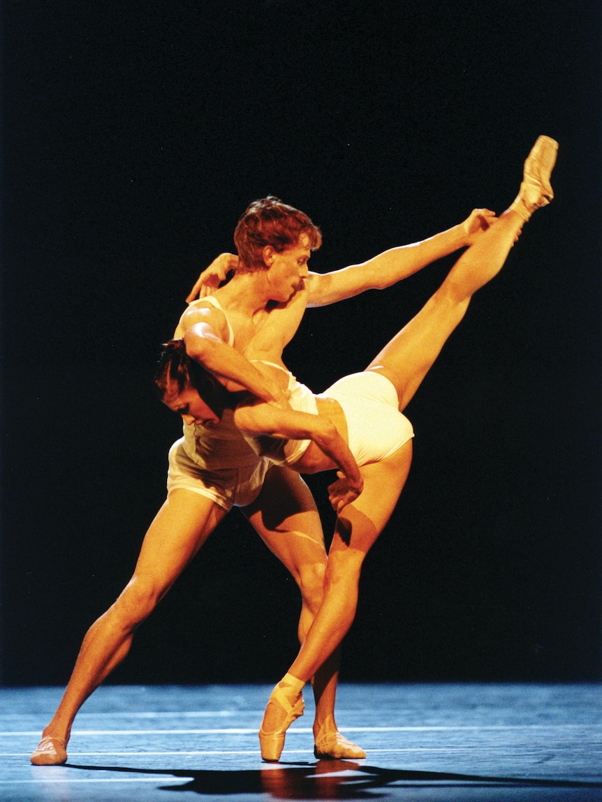 A male and female ballet dancer posed mid-performance on stage. 