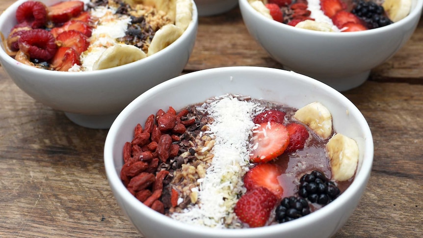 A bowl of acai with fruit and goji berries.