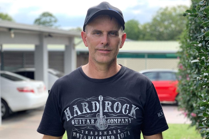 Craig Blackburn stands in front of a house wearing a cap.