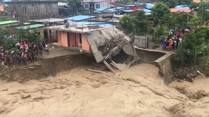 water washes away part of a house as it runs through Dili