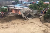 water washes away part of a house as it runs through Dili