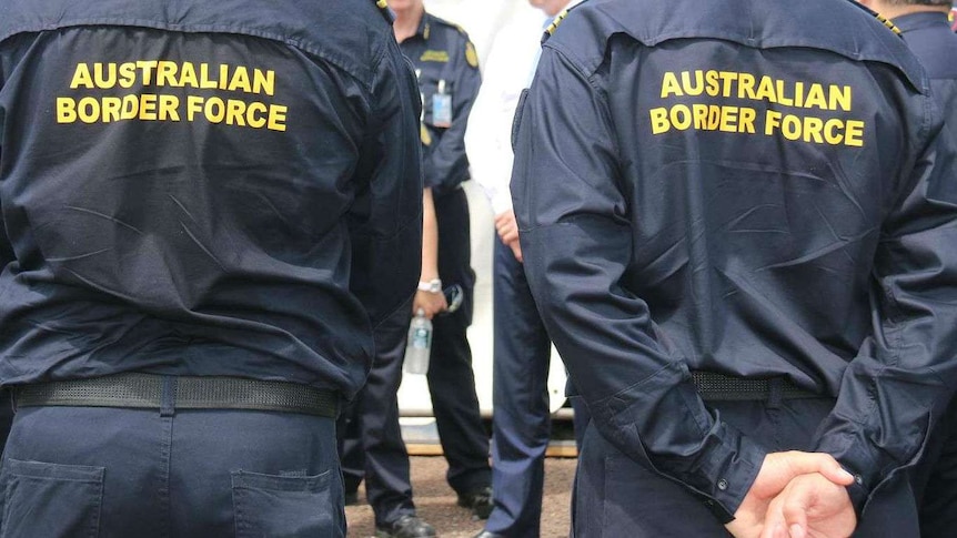 An image of the backs of two Border Force officers, their organisation clearly shown by signs on their backs