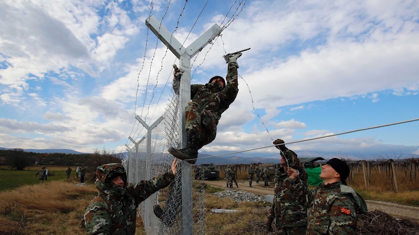 Macedonian soldiers erect a barbed wire fence on the Macedonian-Greek border