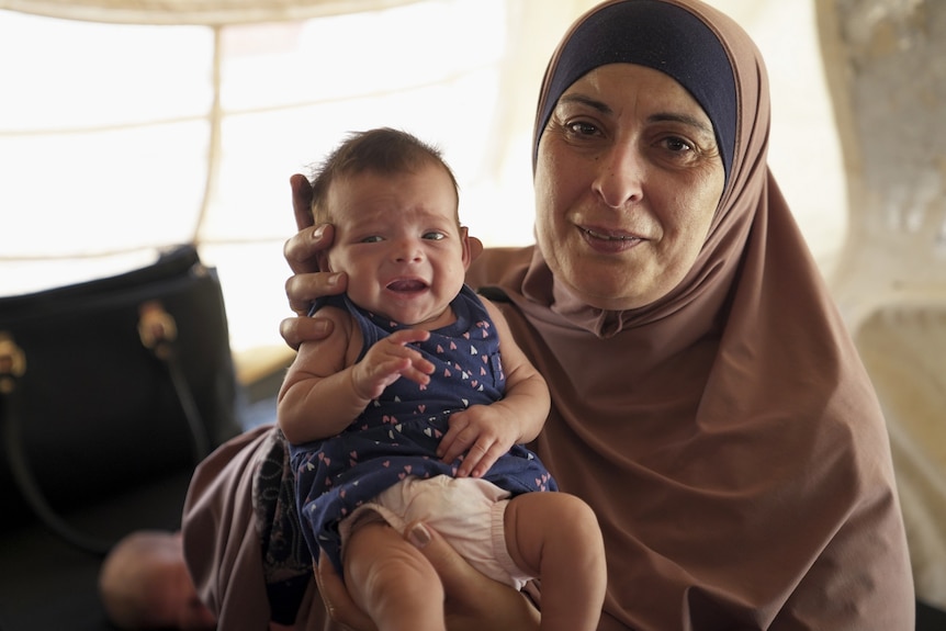 Hiam Zahab cuddles an Australian baby in the al-Hawl camp in Syria