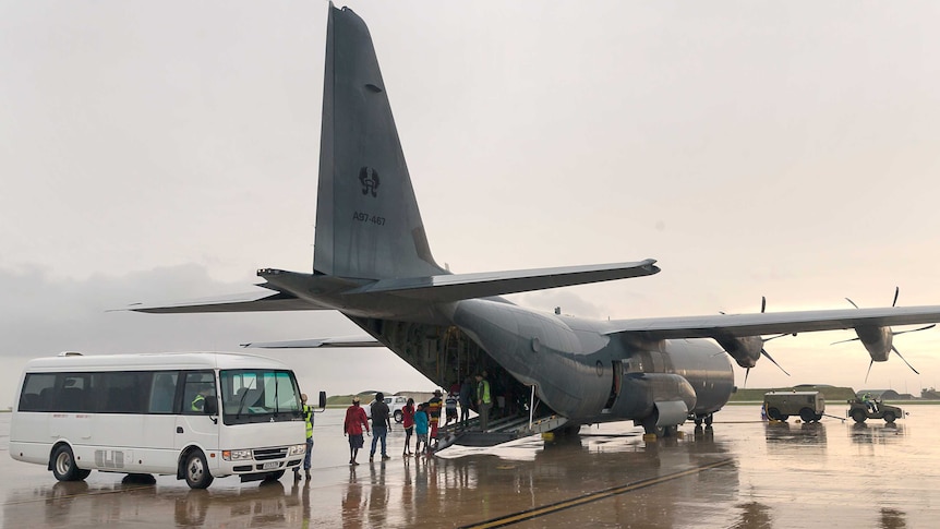 People walk into the back of a plane on the tarmac