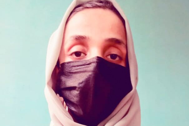 A close up of a woman wearing a face mask and pink hijab.