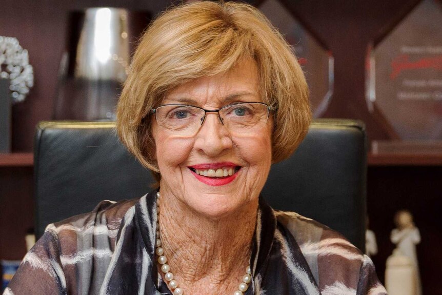 Margaret Court sits in a chair smiling at the camera.